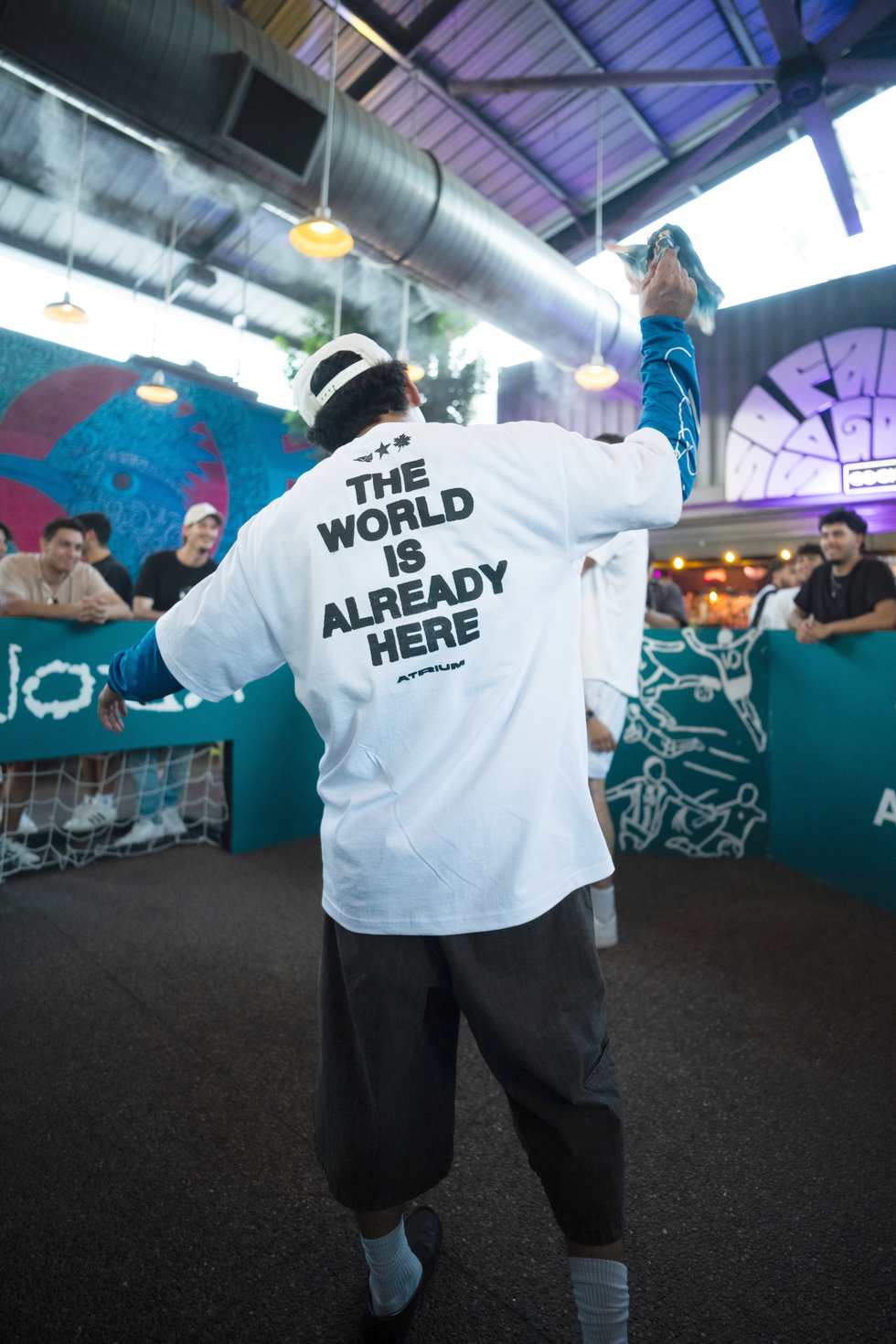 A guest dancing in a "The world is already here" shirt